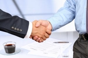 The Close-up image of a firm handshake between two colleagues under contract